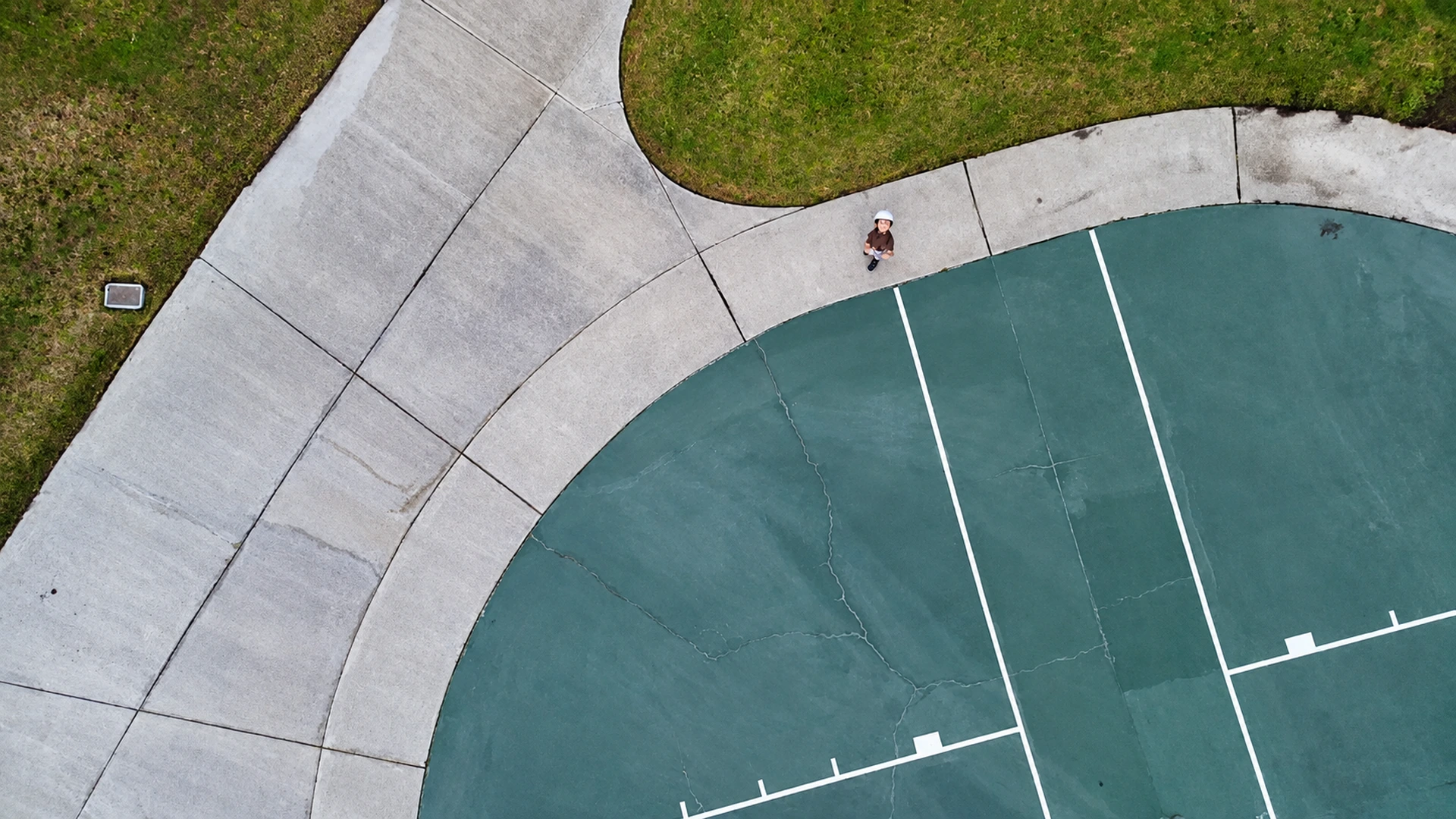Aerial drone view of a curved sports court and a person looking up