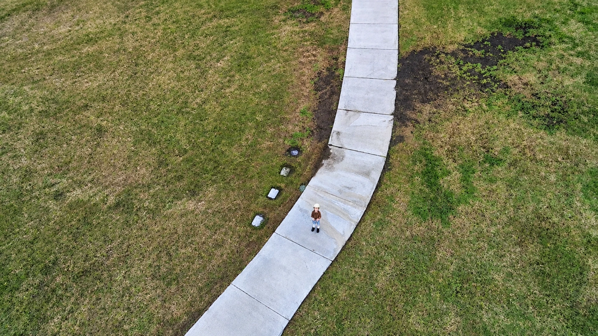 Aerial drone view of a winding path through a grassy park