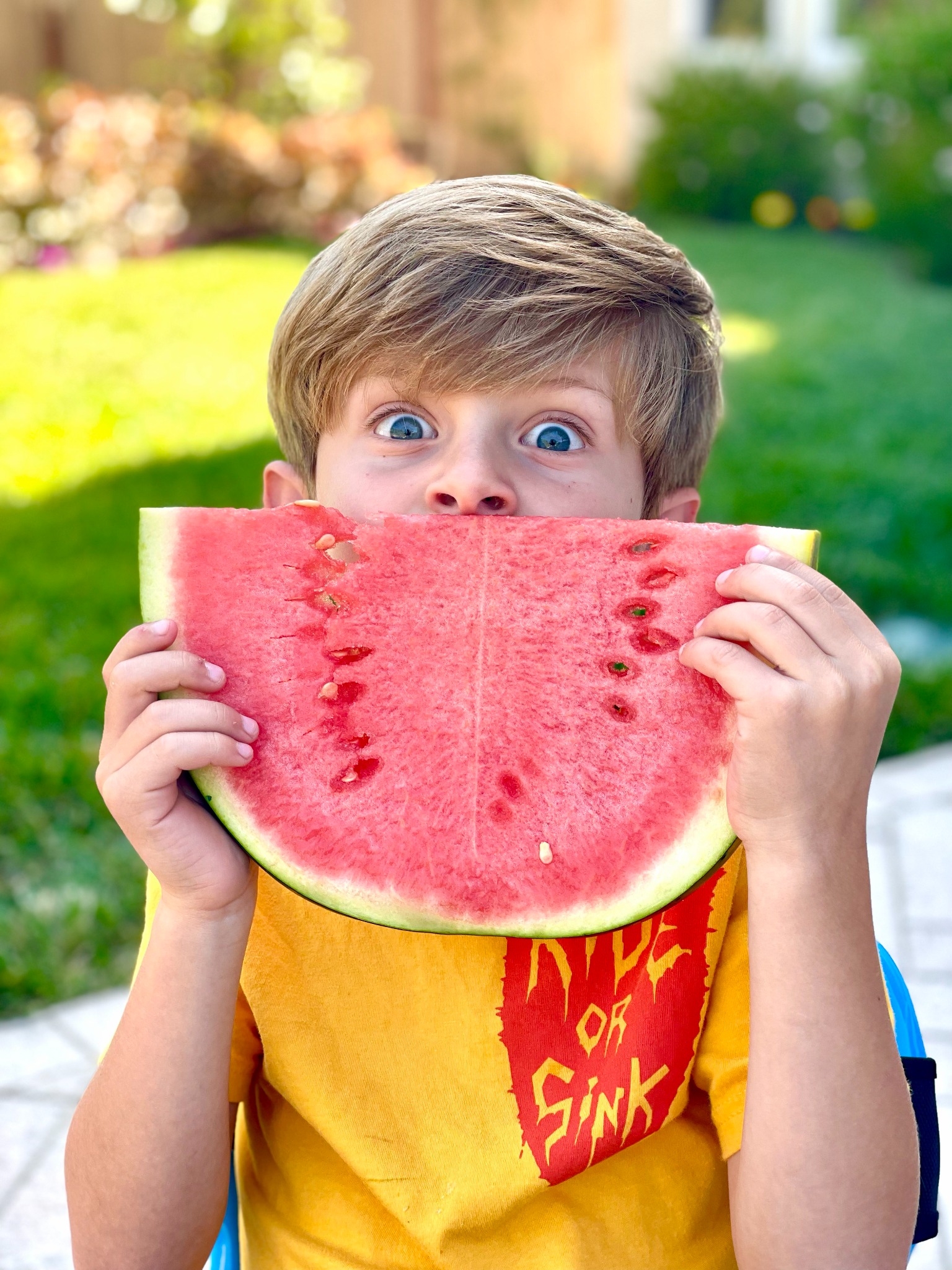 Skye making a funny face behind a large slice of watermelon